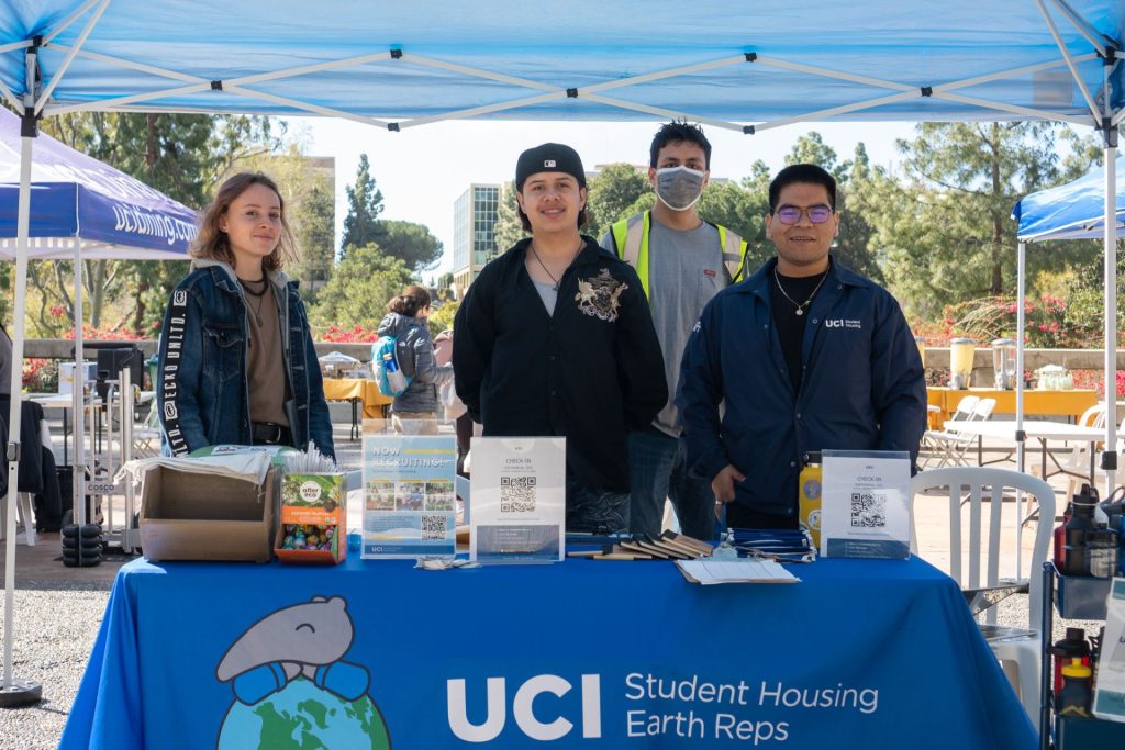 four people standing behind a table with a blue table cloth that says Student Housing Earth Reps